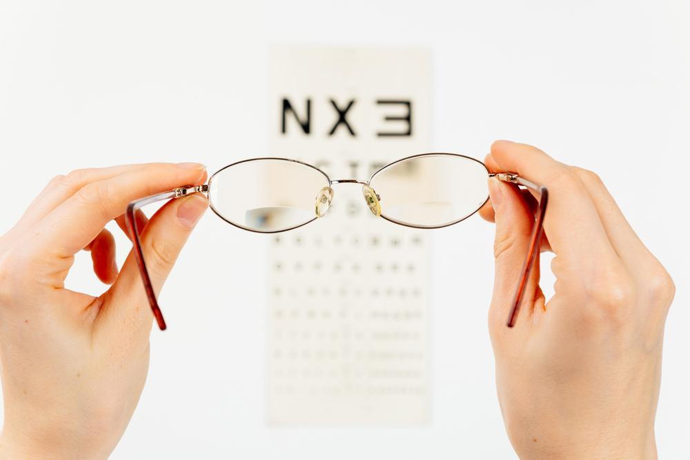 person holding up glasses to see en eye exam chart during an eye exam with her optometrist in Elko