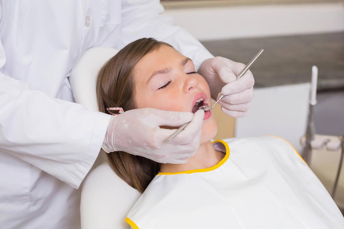 pediatric dentist commack checks girl's teeth