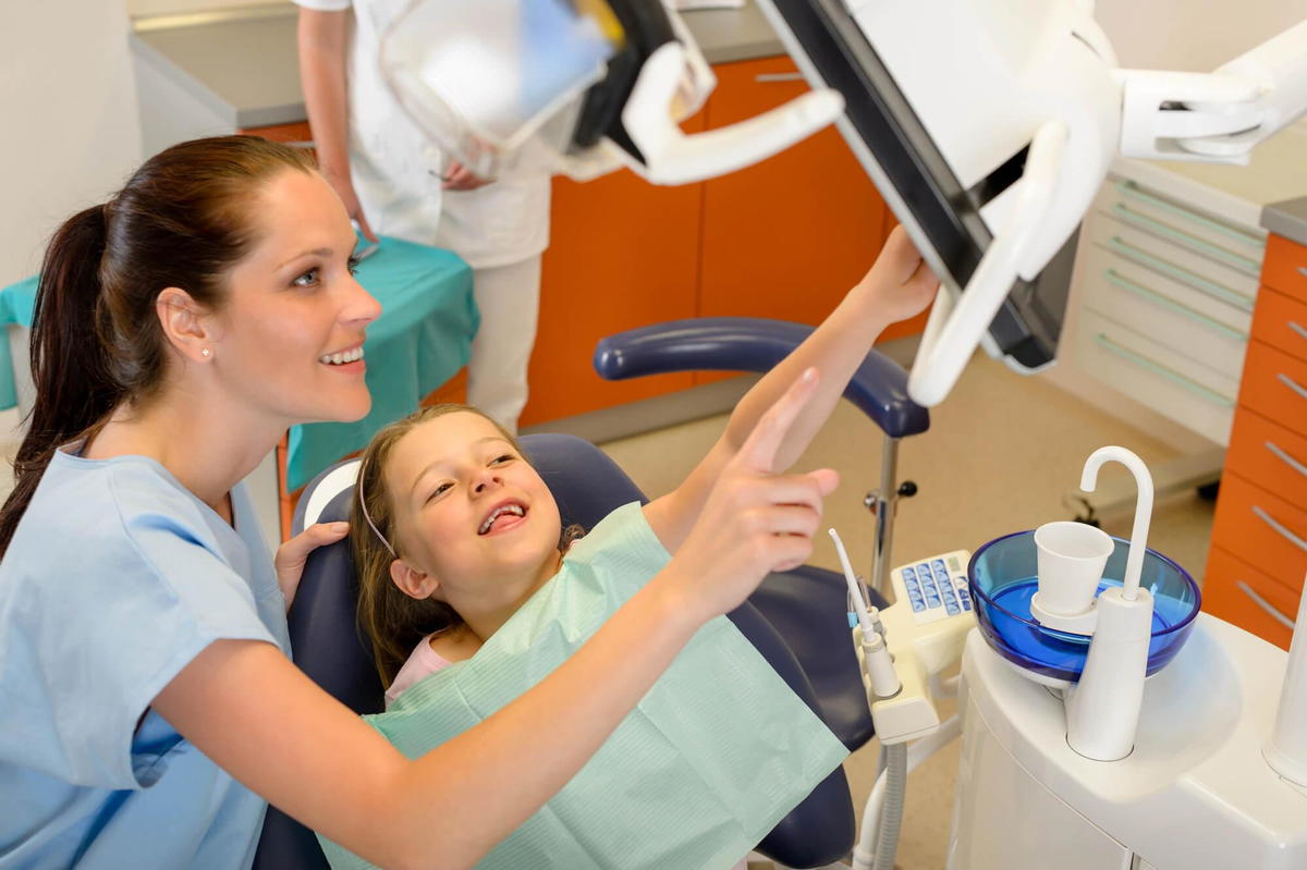 dentist explaining to little girl how Children sleep dentistry commack works