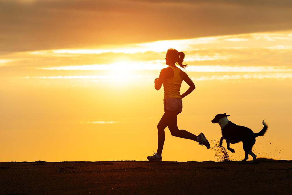 Woman running with her dog in summer.