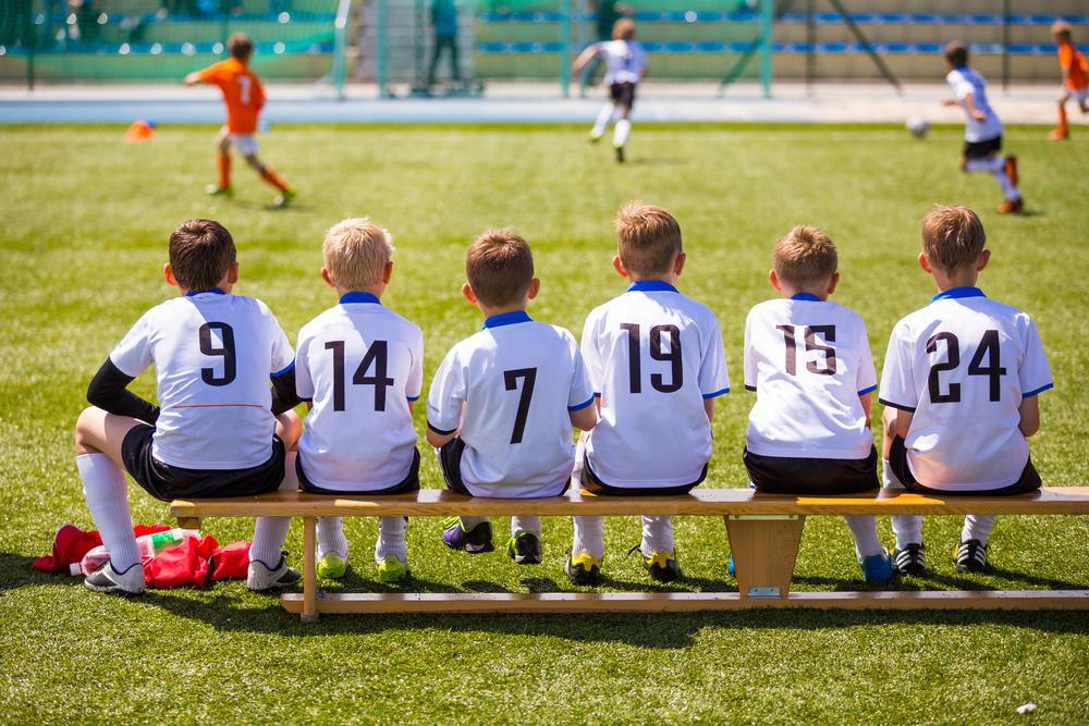 Kids sitting on bench during soccer game