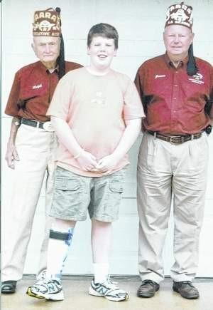 Eleven-year-old Garrett Bonneville, center, with LaGrange Shriners Ralph Thompson, left, and James Shelnutt in LaGrange after his surgery at a Shriners Hospital for Children in Greenville, S.C.