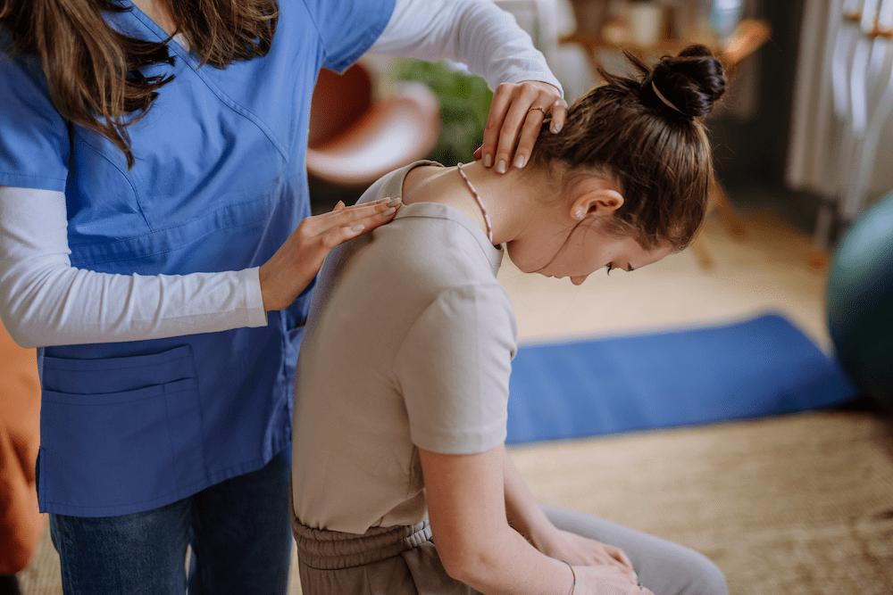 female doctor making chiropractic assessment to teenage patient for improved spinal alignment and posture