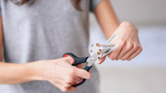 Image of a person cutting cigarettes with scissors