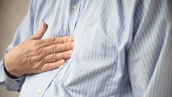 Closeup image of person holding chest with heartburn