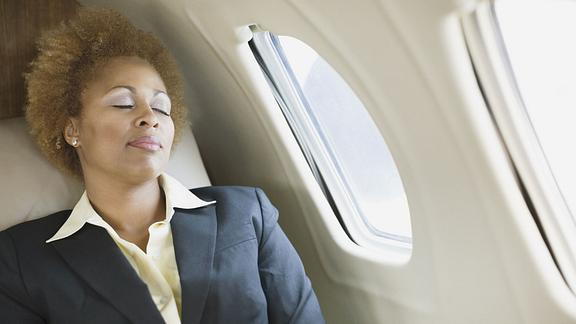 Image of woman napping in the window seat of an airplane