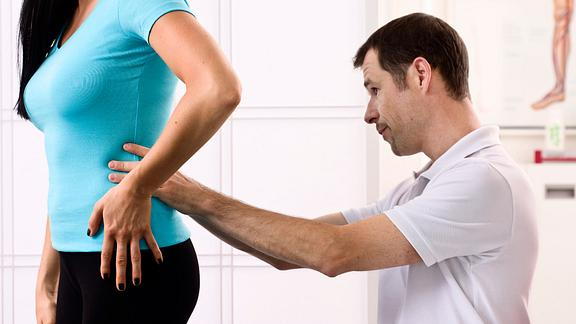 physical therapist examining patient's lower back