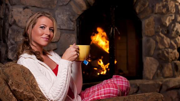 Image of woman drinking tea in front of the fireplace