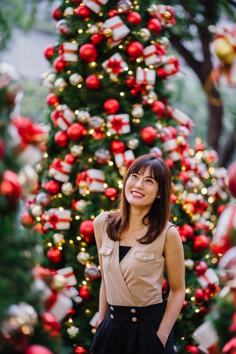 selective-focus-photography-of-smiling-woman-standing-beside Christmas tree